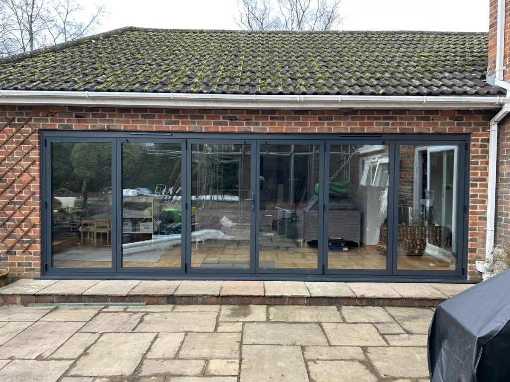 Anthracite aluminium bi-fold door fully closed on a brick extension